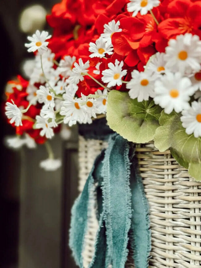 red and white flowers in basket with blue ribbon