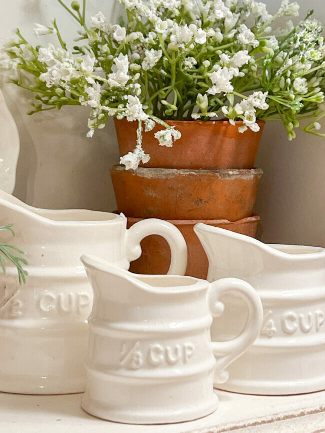 white ironstone measuring cups with clay pots and flowers