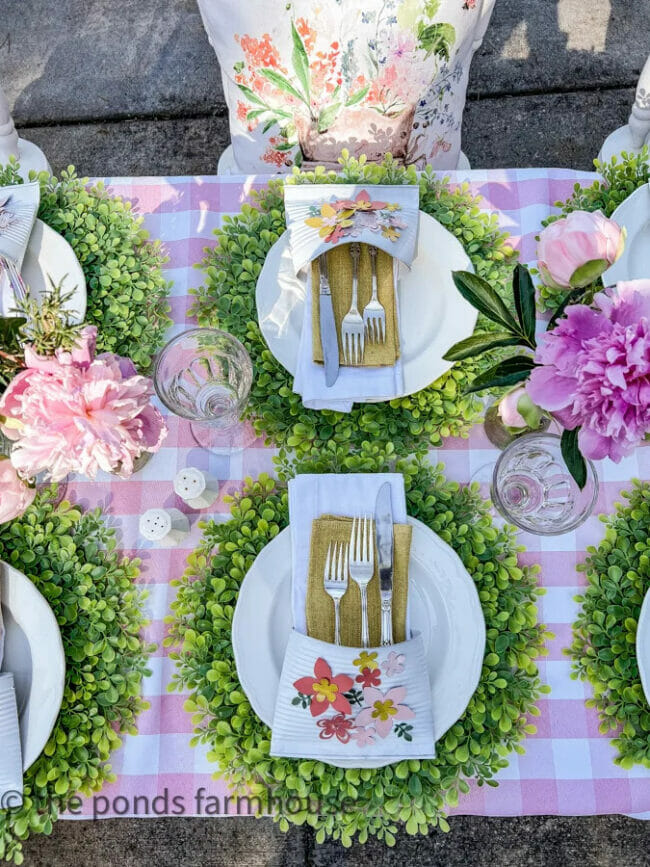 pink and green table setting with boxwood chargers