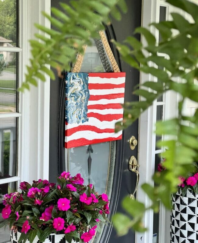 painted flag hanging on front door with pink plants