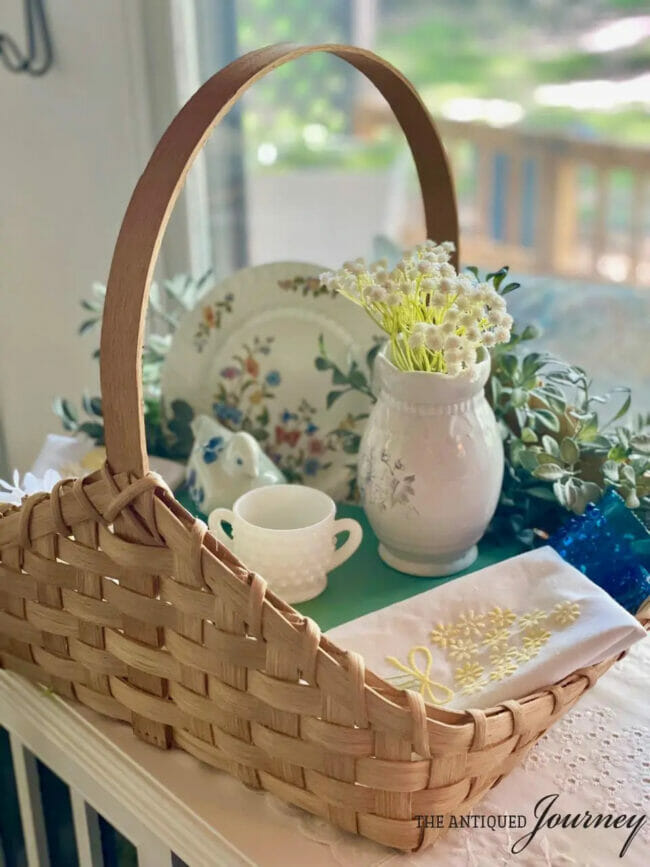 old basket with vintage dishes and flowers