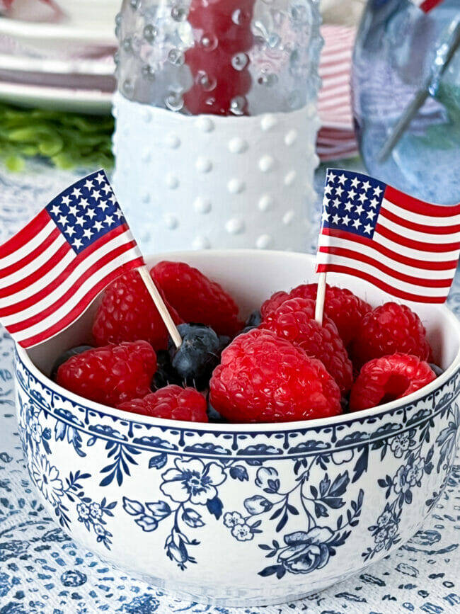 blue and white bowl with red fruit and mini flags