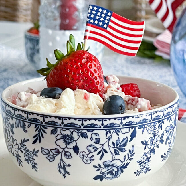 close up of blue and white bowl with fruit salad and strawberry with flag
