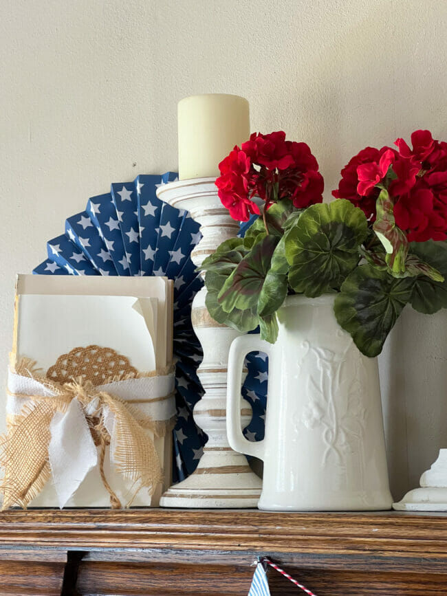 ironstone pitcher with red gardenias, white books, candle