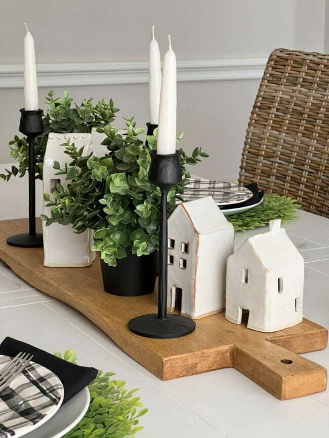 white pottery houses with boxwood and candles sitting on bread board