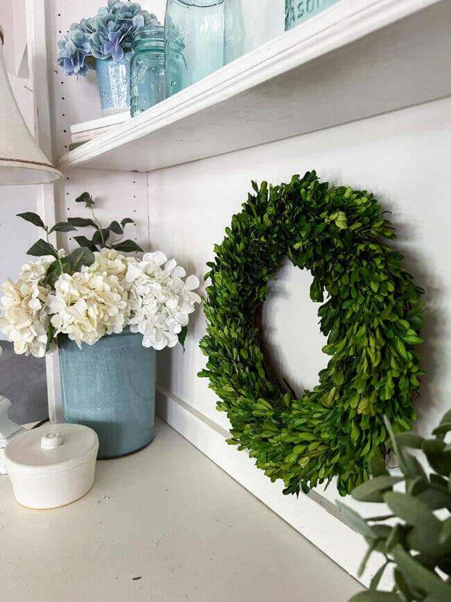 boxwood wreath with blue crock and hydrangeas