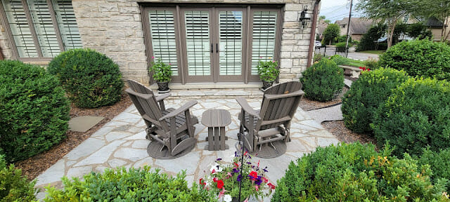 back of house with seating on patio and bushes