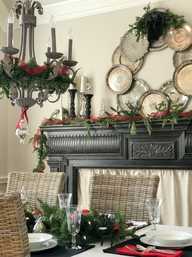silver tray wreath on black mantel with chandelier and greenery
