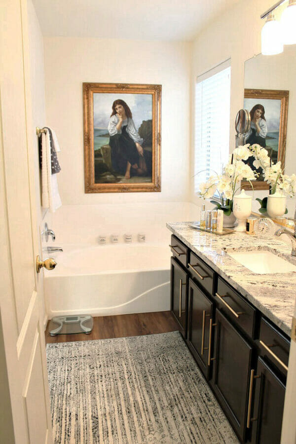 bathroom with painting over tub and flowers on sink