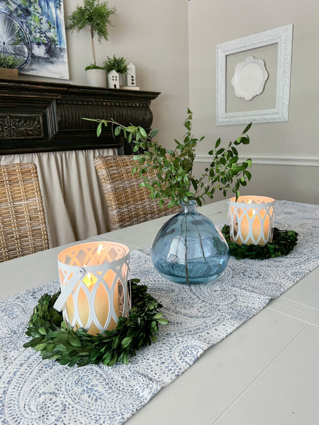 Boxwood wreaths under candles with blue vase with boxwood stems