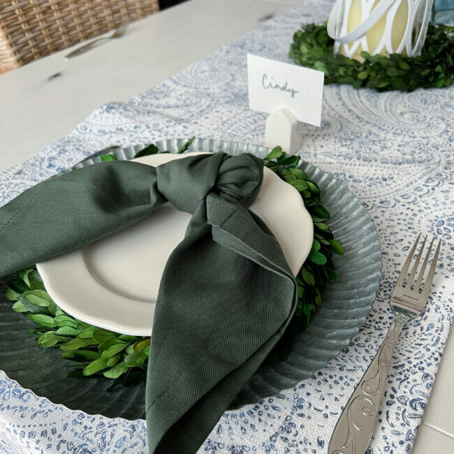 place setting with green napkin, boxwood wreath under white plate