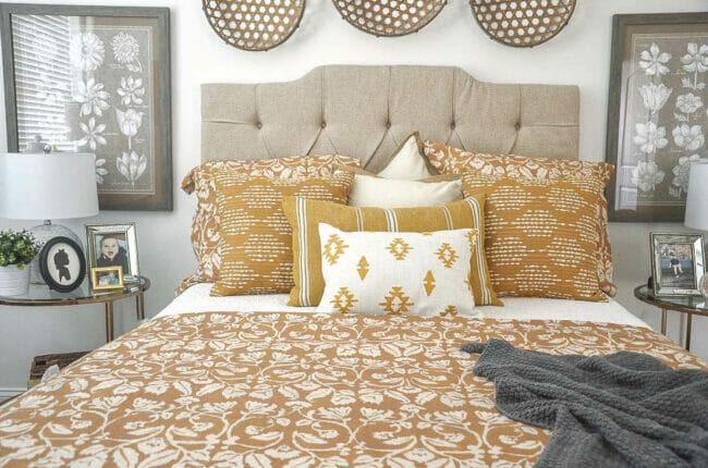 bed with gold pillows, gray blanket and baskets hanging over headboard