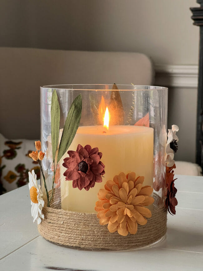 glass vase with flowers and twine on outside with lit candle