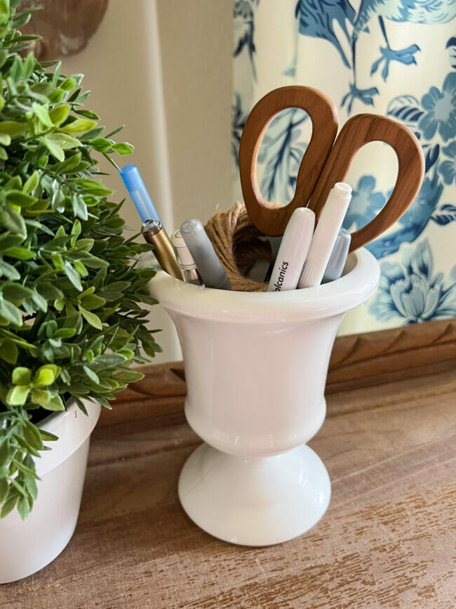 milk glass as office supply holder with pens and scissors and green plant