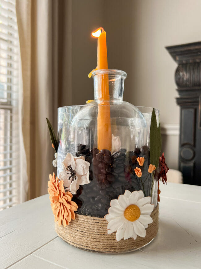 jar with lit candles, flowers on outside and coffee beans