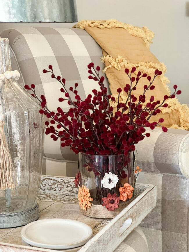 side table with clear lamp, checked chair and vase with dark red fuzzy stems