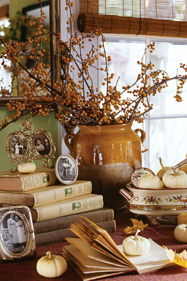 gold pot with berries, books, pumpkins and small framed photos
