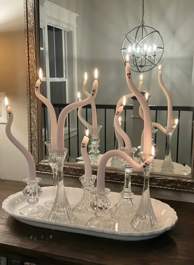bent white candles with ghost faces in glass candlesticks