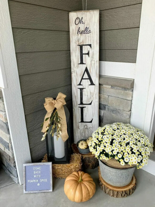 wooden fall sign, white mum and pumpkins with lantern on porch