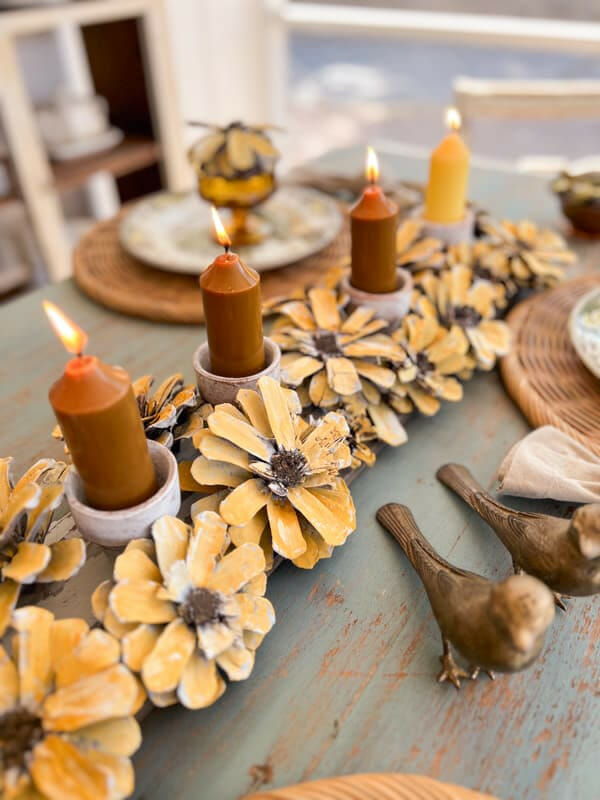 yellow pinecone centerpiece with candles and brass birds