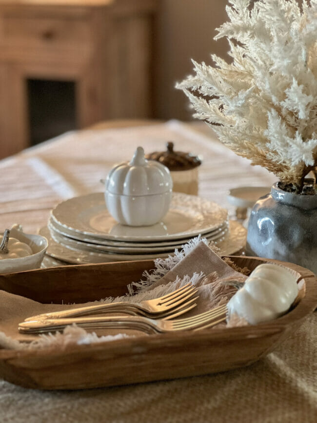 close up of silverware in wooden bowl, white stacked plates with pumpkin bowl on top