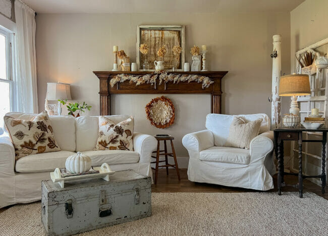 white sofa and chair with mantel , gray footlocker and fall accessories