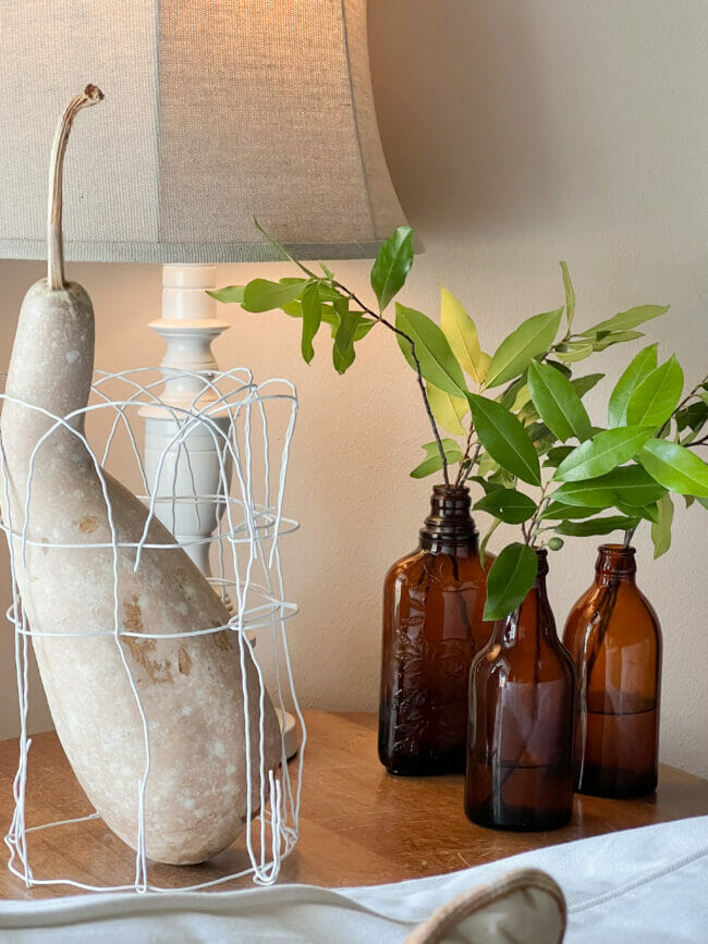 gourd in wire vase, amber bottles with green stems and lamp