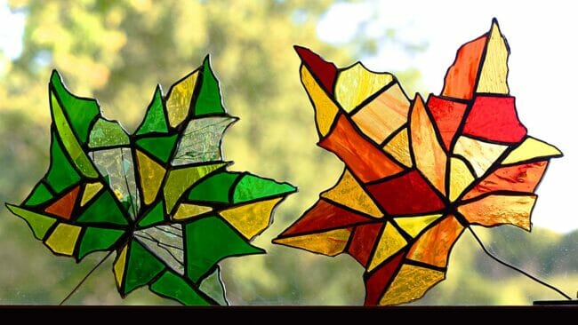 2 stained glass leaves in window in green and gold and red and gold