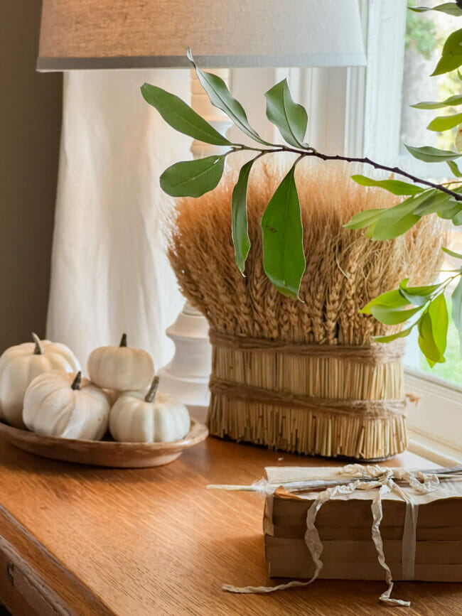 wheat, white pumpkins and stacked books with feather