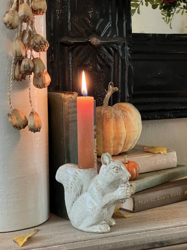 white squirrel candle holder with pumpkin and stacked books