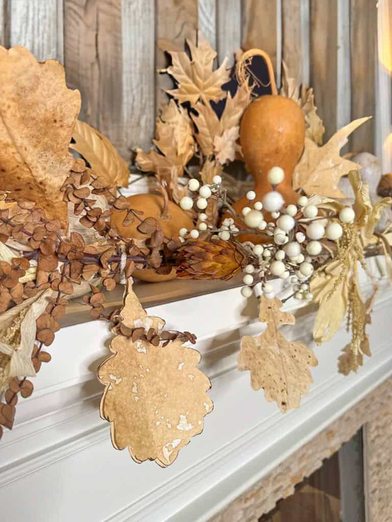 mantel with paper leaf garland, gourds and white berry stems
