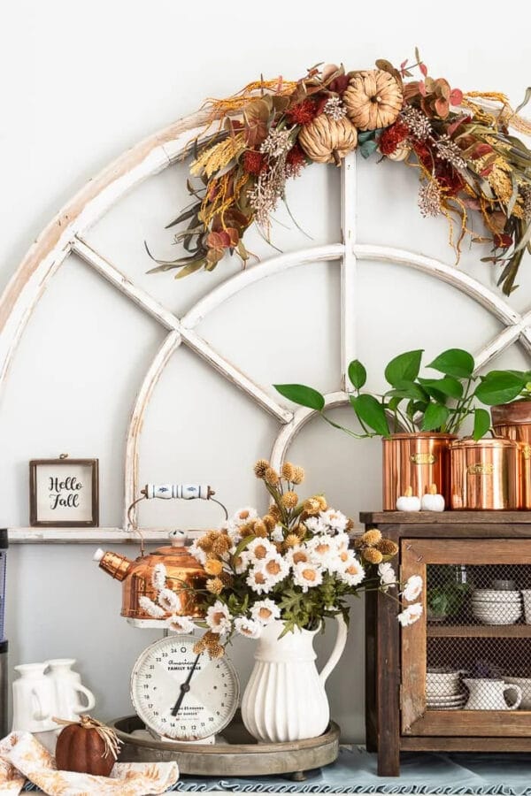 large window arched window frame with copper pots and autumn flowers