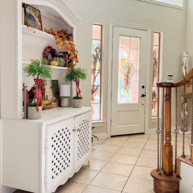 entryway with door and hutch decorated for fall