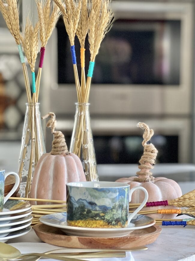 Artsy cups and plates with a wheat and pumpkin centerpiece