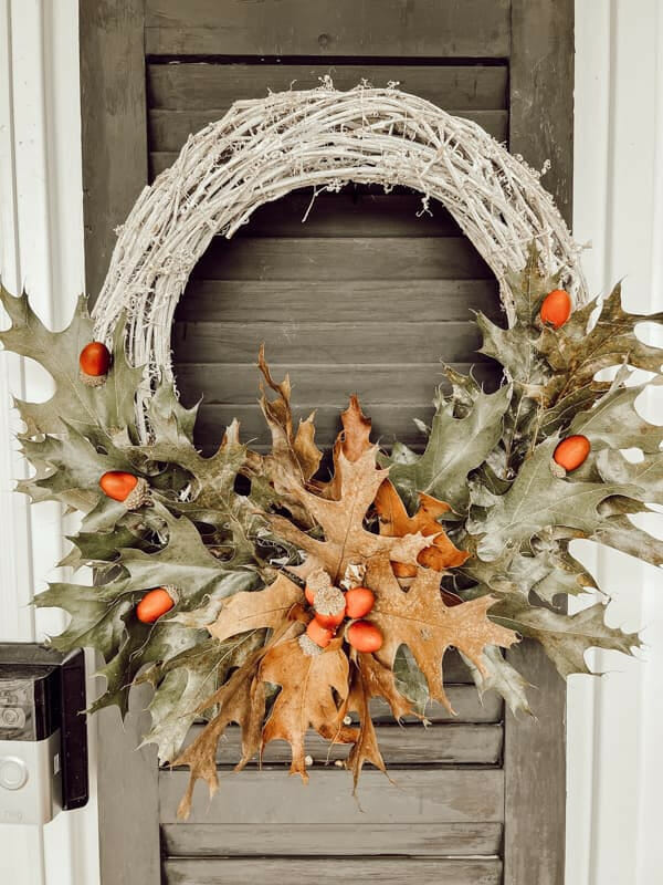 leaf wreath in green and brown hanging on shutter