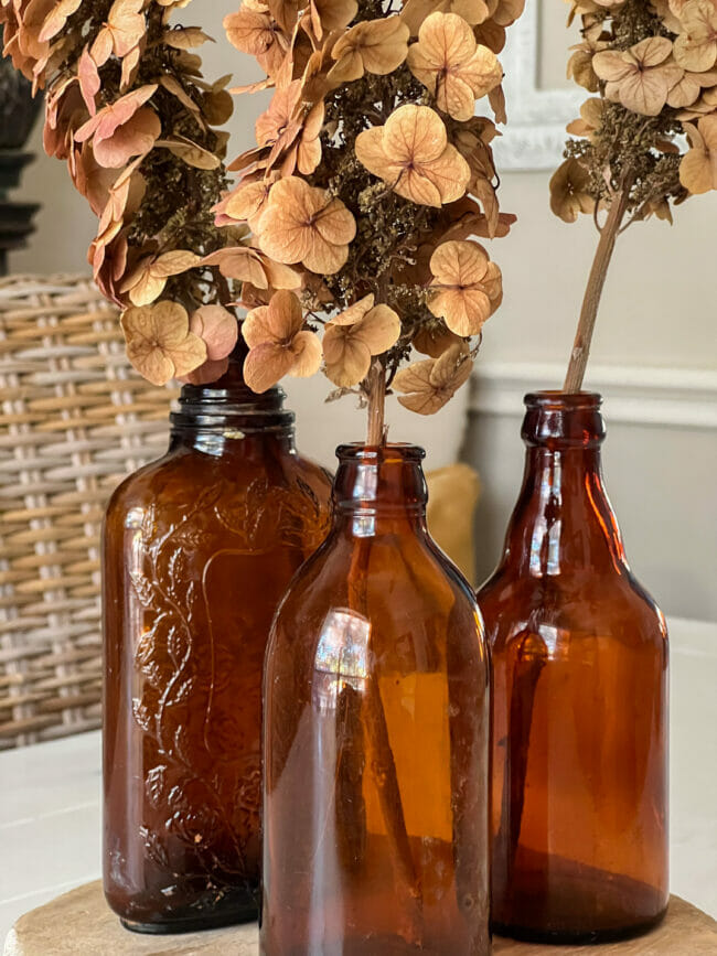 close up of 3 amber bottles with dried flowers as a table centerpiece
