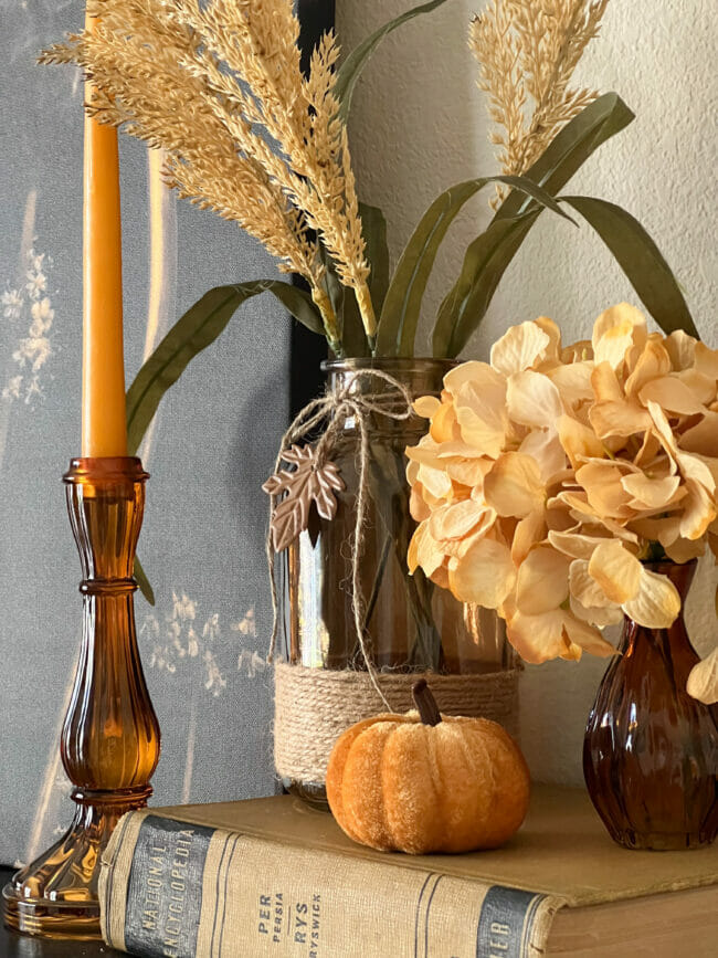 amber glass candle, vase with flower, and book