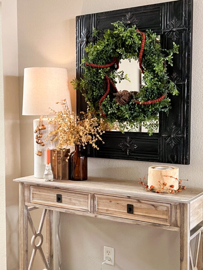 light console table with black mirror, wreath, lamp and fall stems