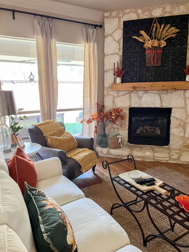 living room with stone fieplace, white sofa, gray chair and fall colors