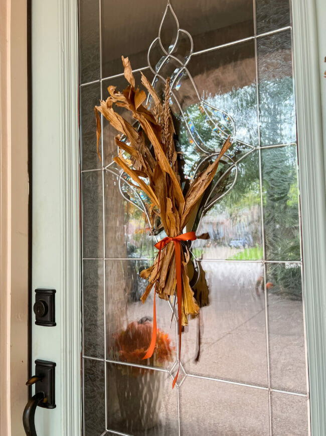 gathered cornstalk pieces hanging on glass door