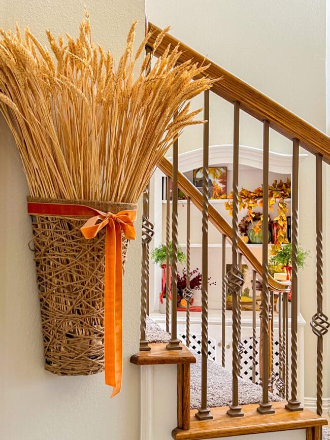 basket hanging on wall with gold stems and orange ribbon by stair railing