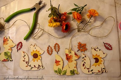 string of wooden foxes with flowers and wire cutters