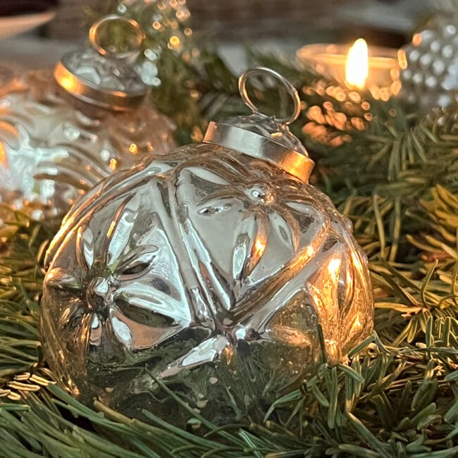 silver ornament with greenery around it