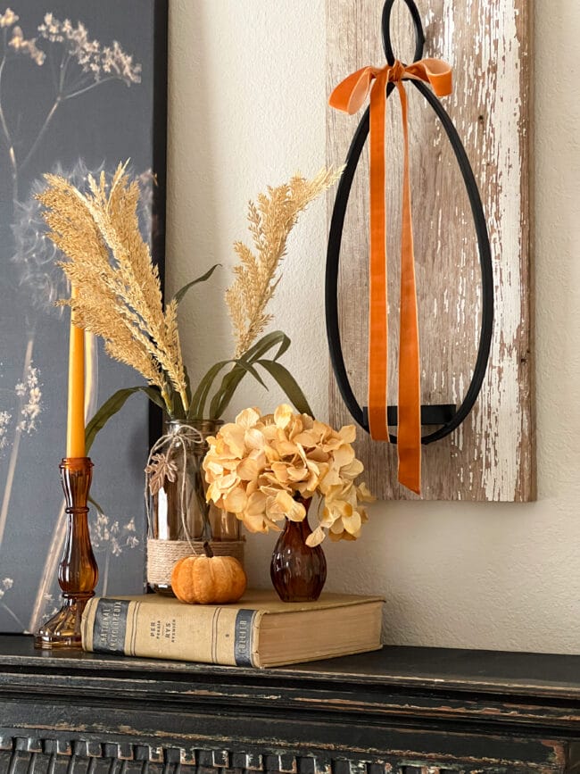 gold book, brown bottles with stems and a candle sconce on wall