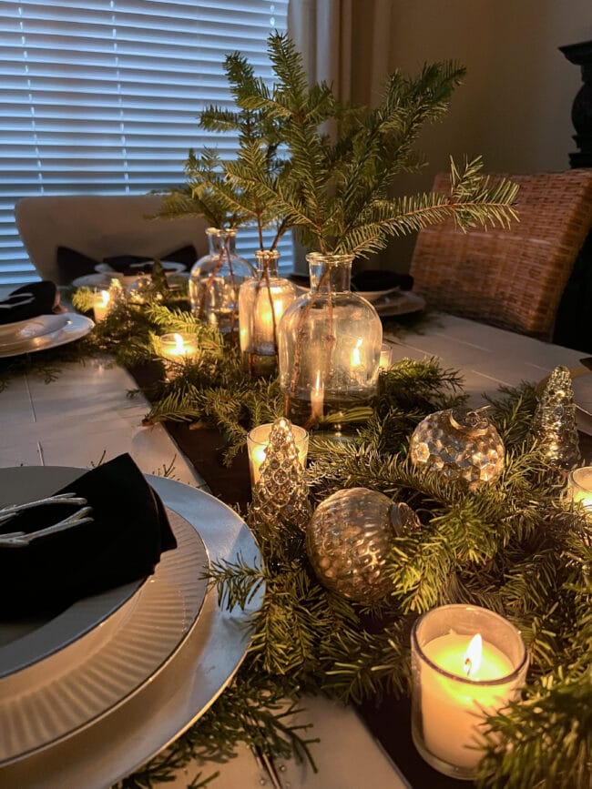 table centerpiece with greenery, candles and silver ornaments