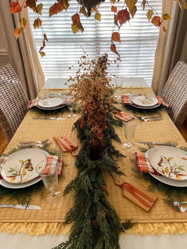 length of table setting with cedar garland, brown bottles and bird plates