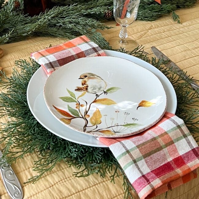 white plates with bird on a stem, plaid napkin and cedar plate charger