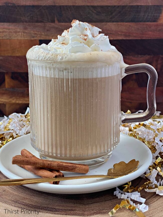 latte in clear cup with cinnamon sticks and gold leaf shaped spoon