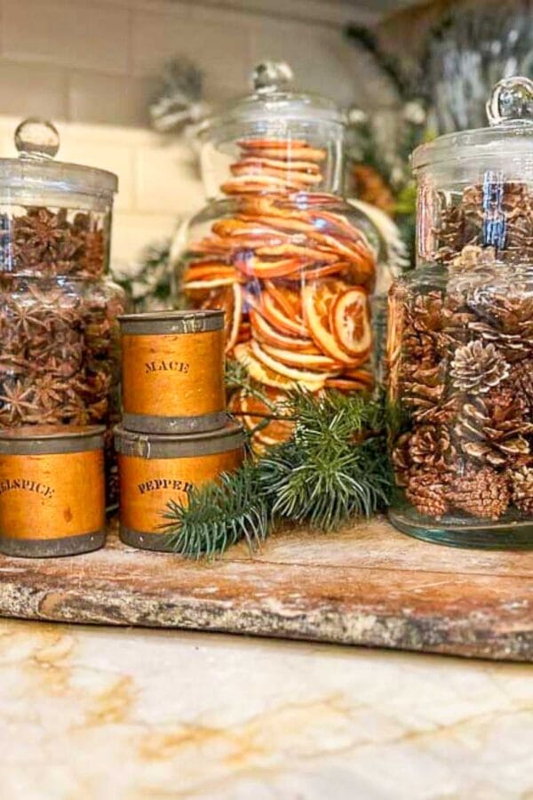 stacks of oranges in jars with pinecones and Christmas greens