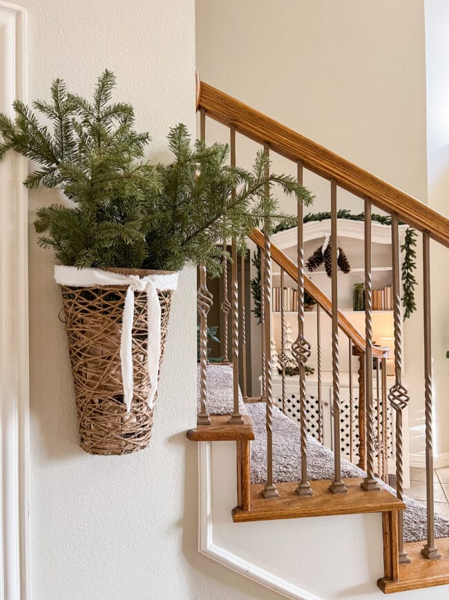 stair rail with hanging basket with Christmas tree stems and hutch in background